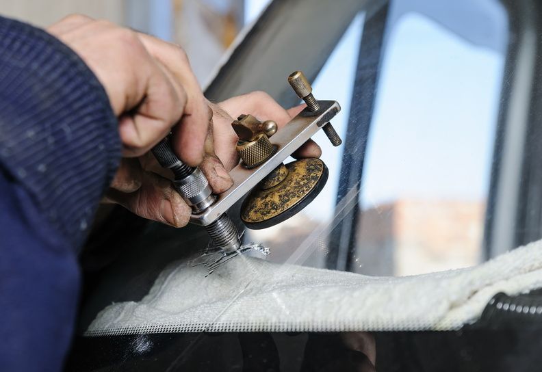 Hand polishing a car windshield with a suction cup tool and white cloth