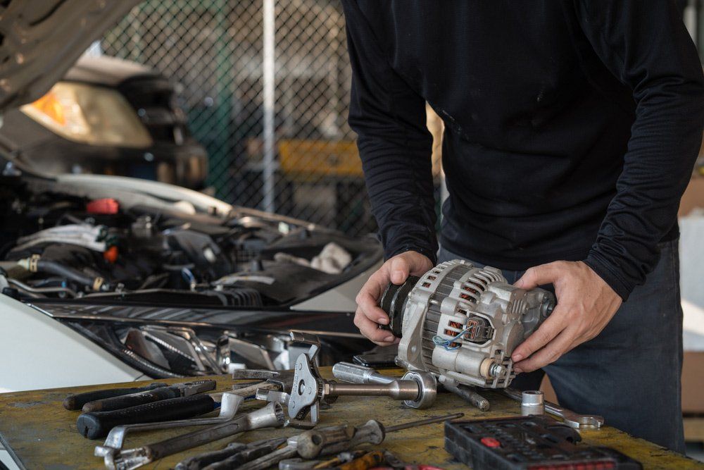 Mechanic Holding Car Alternator — Auto Electrical in Rockhampton, QLD