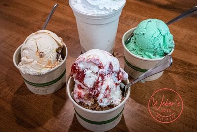 Four cups of ice cream are sitting on a wooden table.