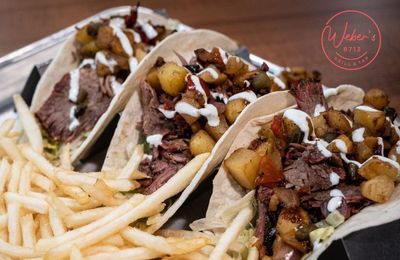 A tray of tacos and french fries on a table.