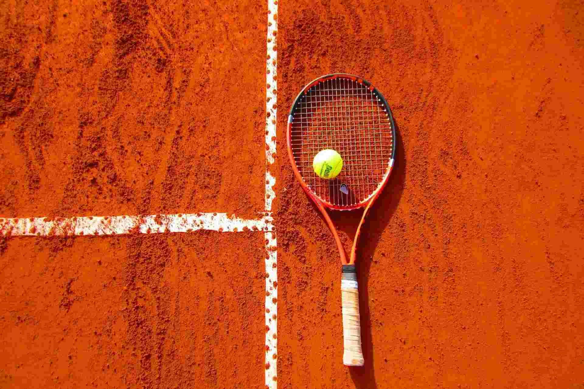 clay tennis court with ball and racquet