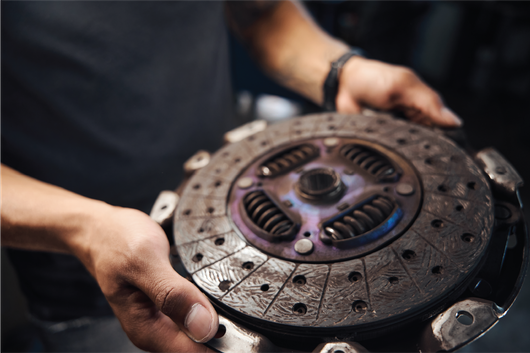 A man is holding a clutch disc in his hands.