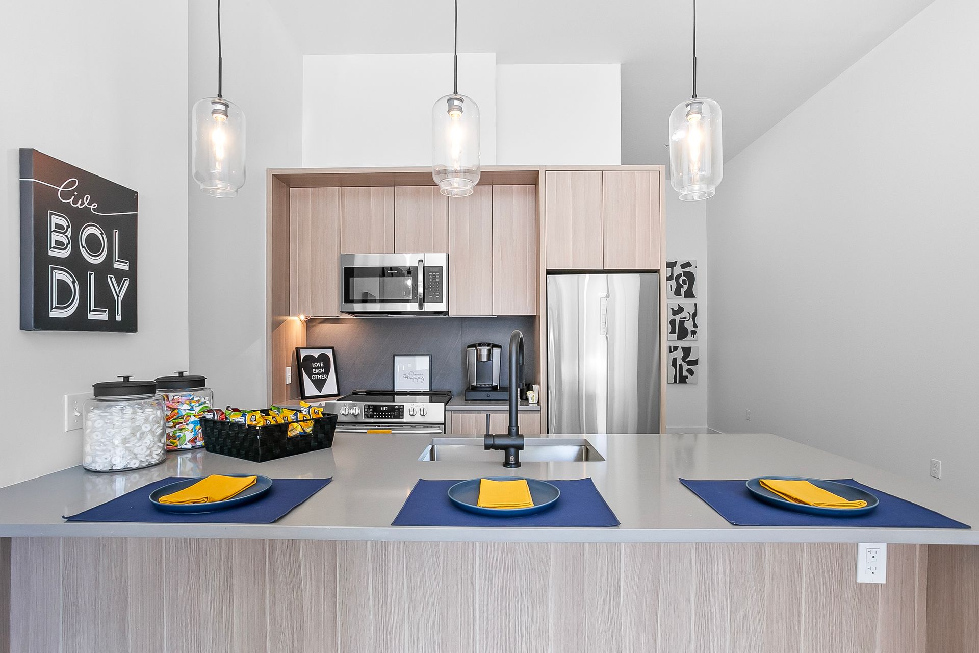 Modern kitchen with a gray countertop island, overhead pendant lights, and stainless steel appliances.