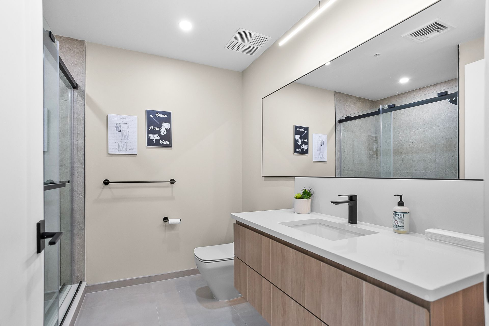 Modern bathroom with shower, vanity, and large mirror; neutral tones.