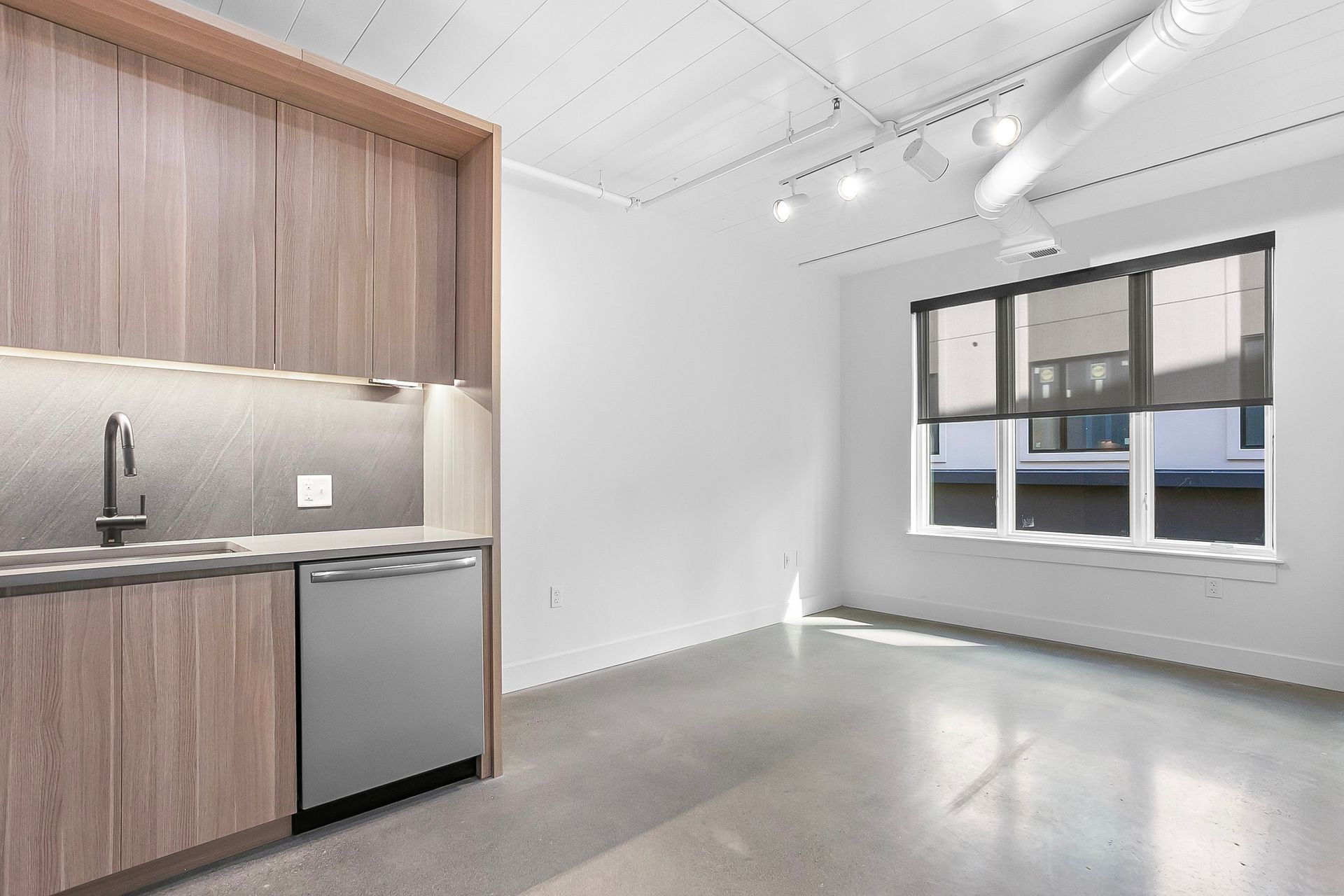Modern apartment kitchen with wooden cabinets, stainless steel appliances, and large window.