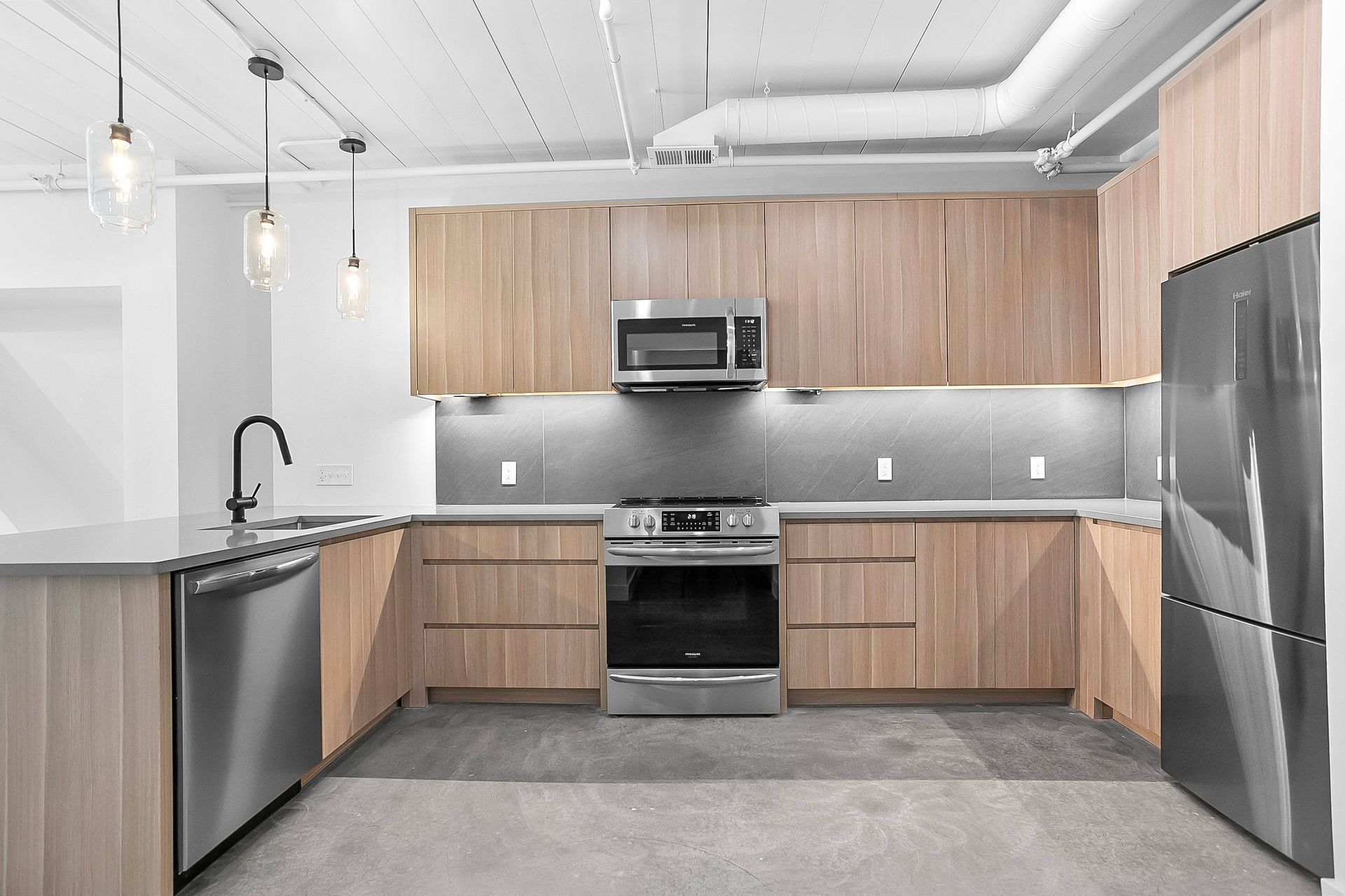 Modern kitchen with wooden cabinets, stainless steel appliances, and a gray countertop.
