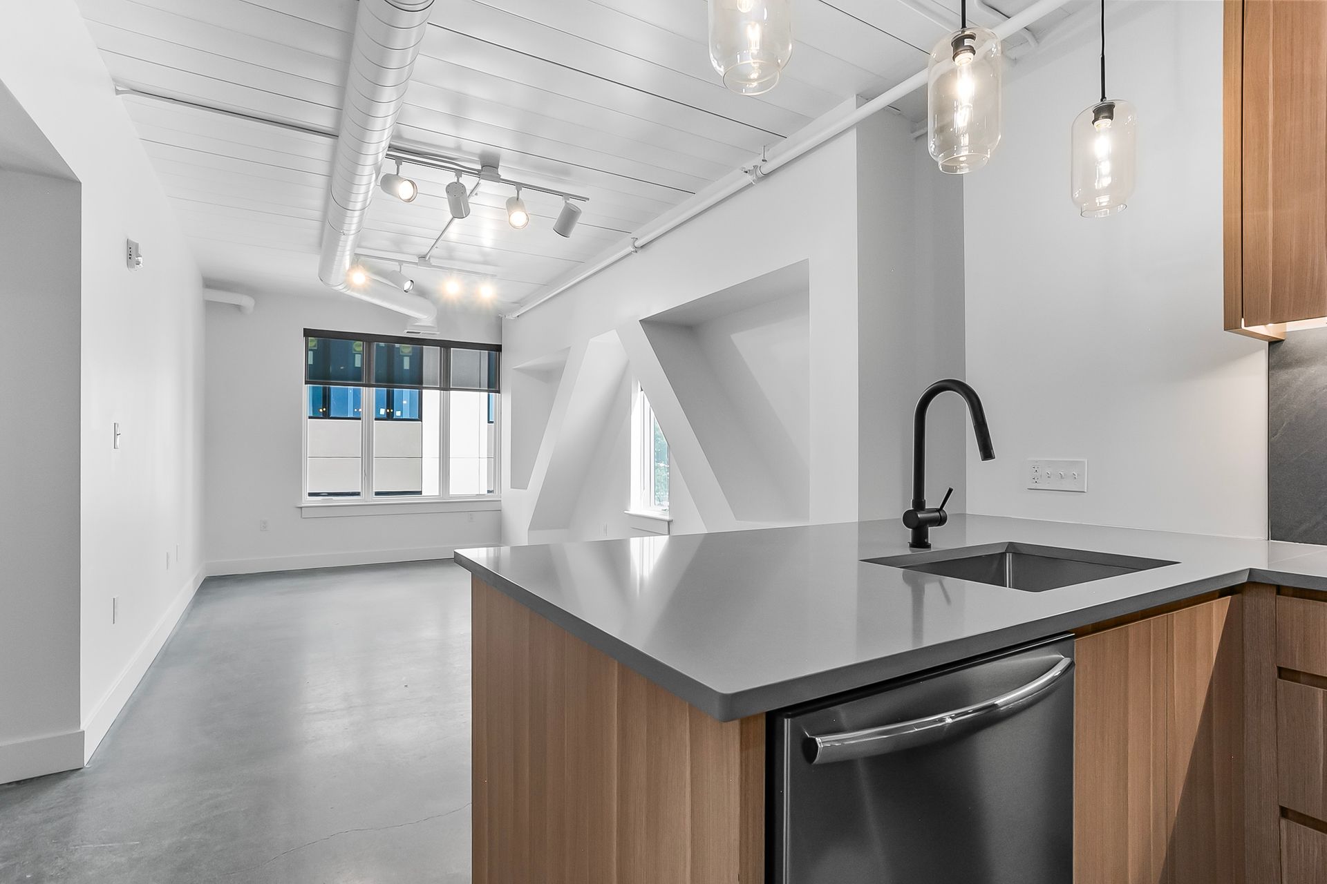 Modern kitchen with stainless steel appliances, light wood cabinets, and gray countertop.
