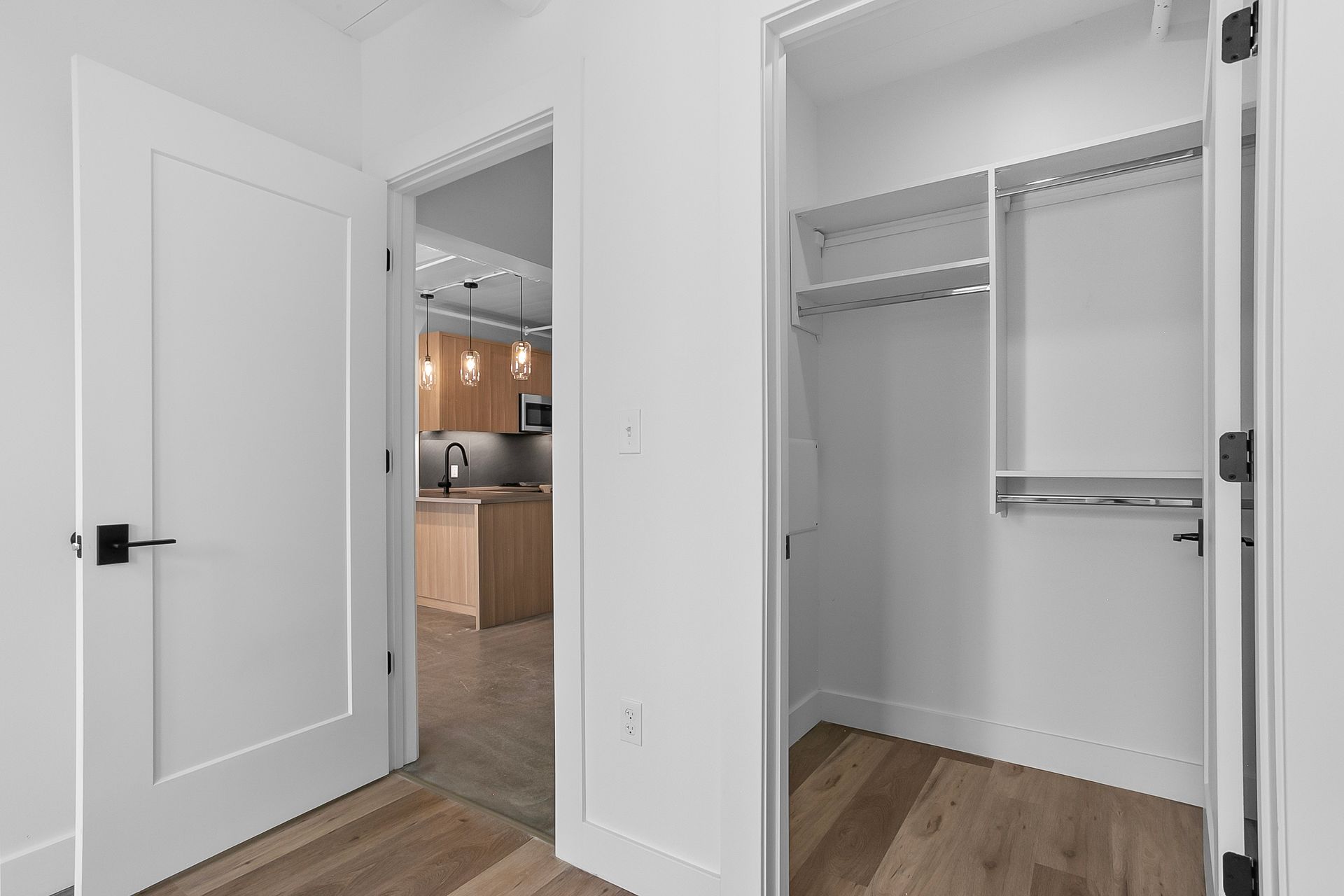 Open white door leads to kitchen, closet with shelves and rod.