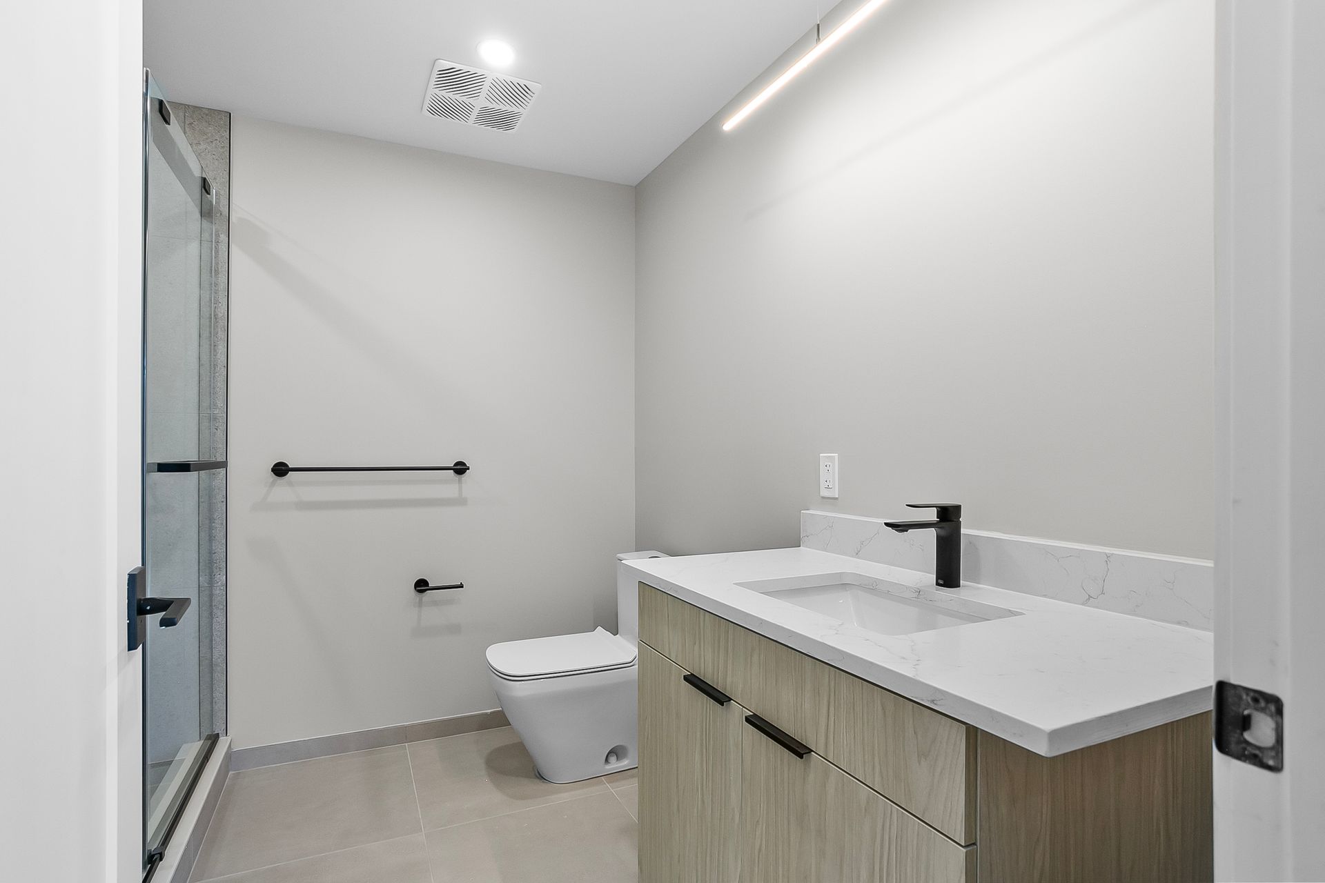 Modern bathroom with shower, toilet, and vanity. Neutral tones, minimalist design.