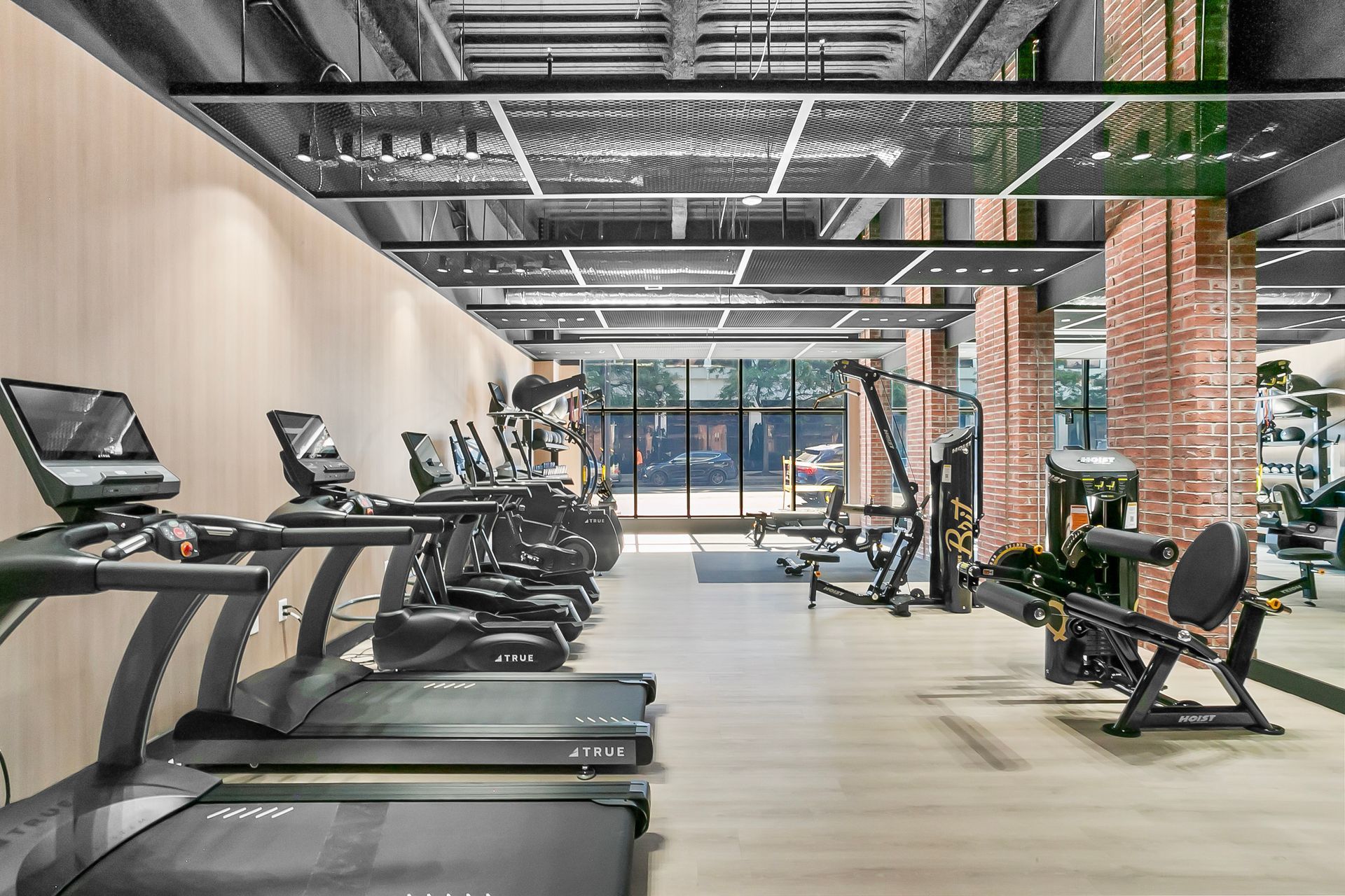 Gym interior with treadmills, exercise bikes, weight machines, and a brick column.