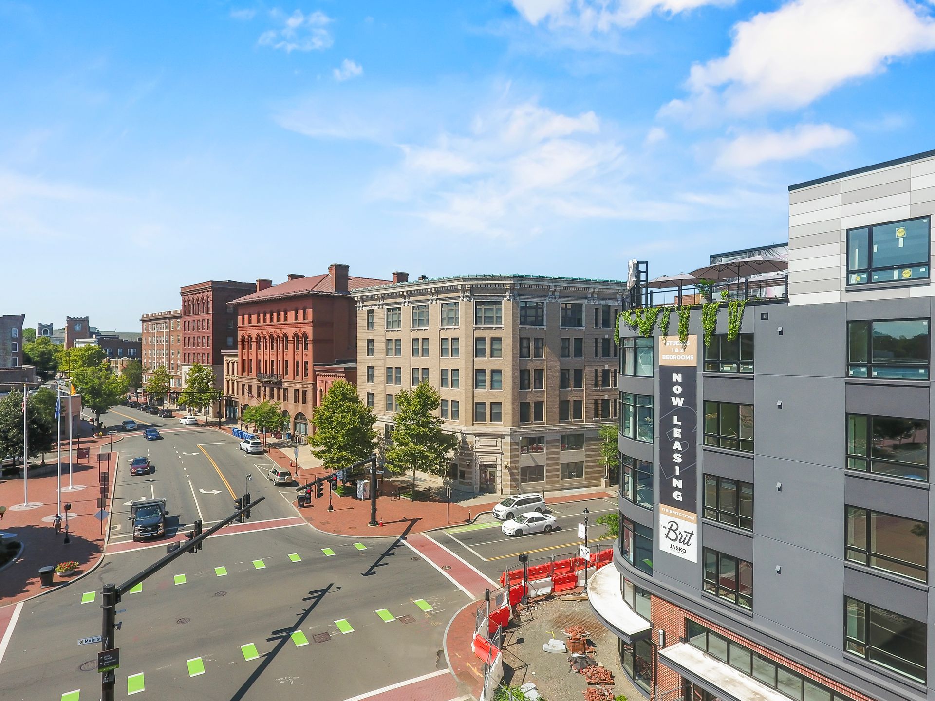 Street view with buildings, traffic, and construction under a blue sky.