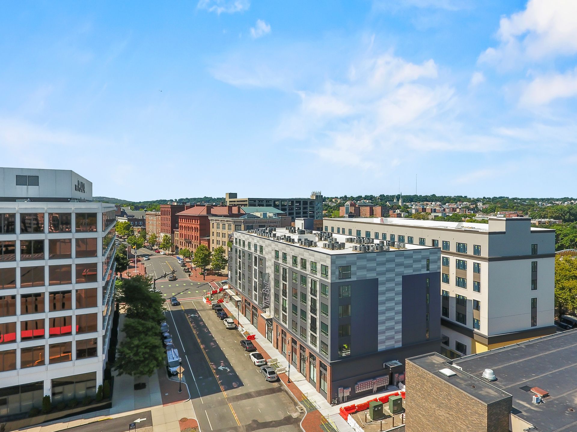 Street scene with multistory buildings, businesses, and cars on a sunny day.