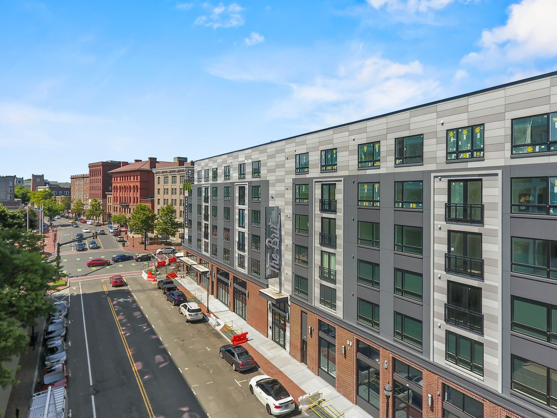 Street view of modern multi-story building with cars and traffic on street.