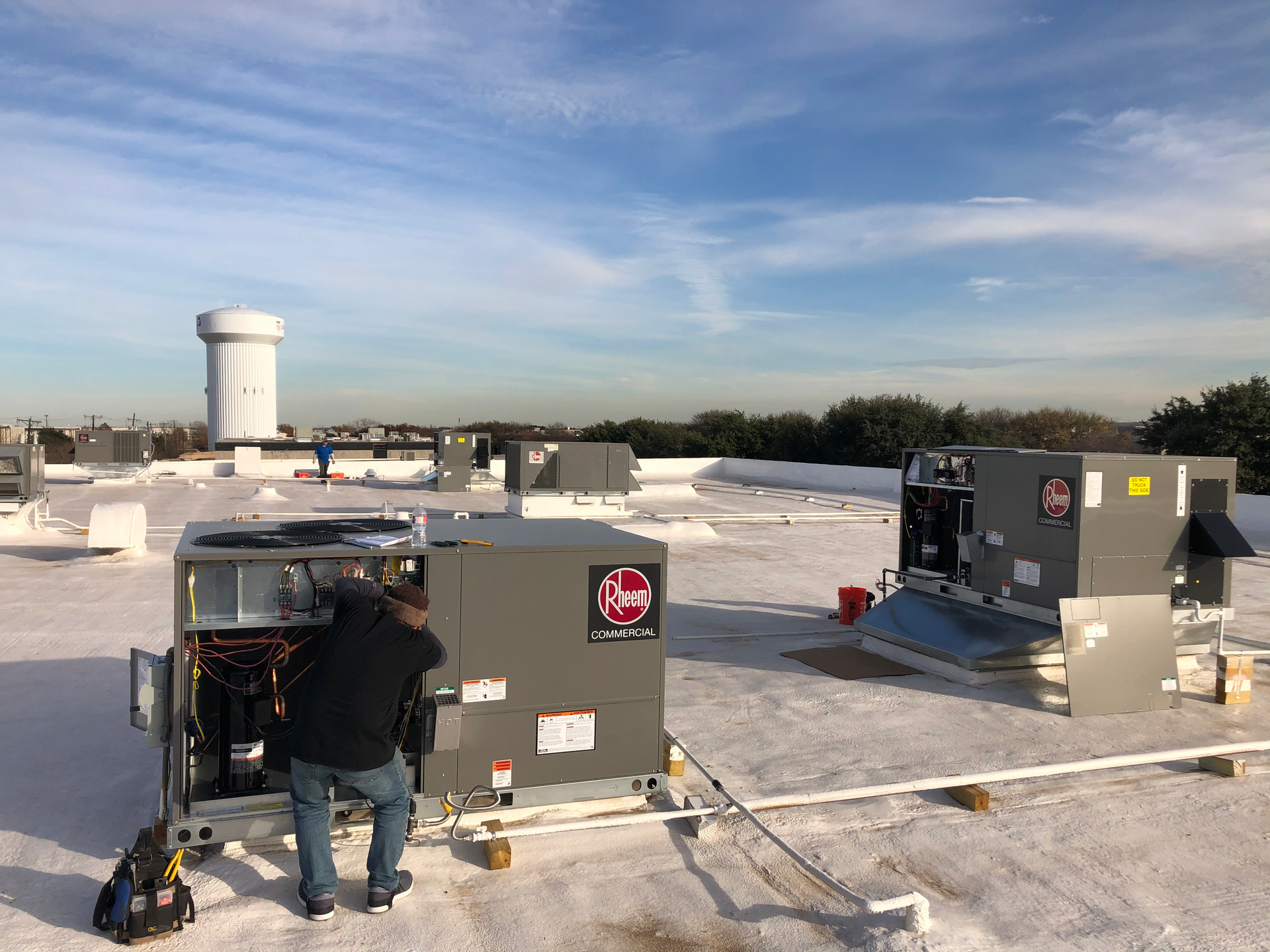 A man is working on a rooftop air conditioning system.