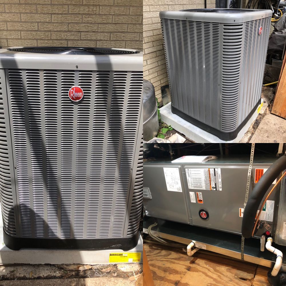 A gray air conditioner is sitting on top of a wooden floor next to a brick wall.