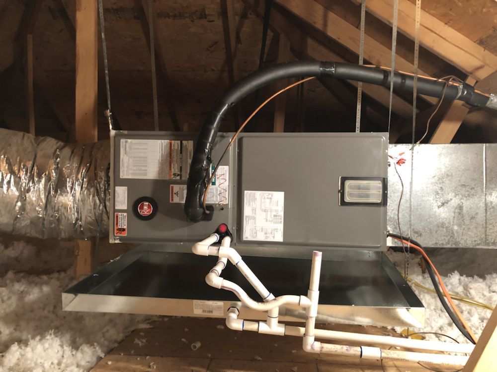 An air conditioner is hanging from the ceiling in an attic