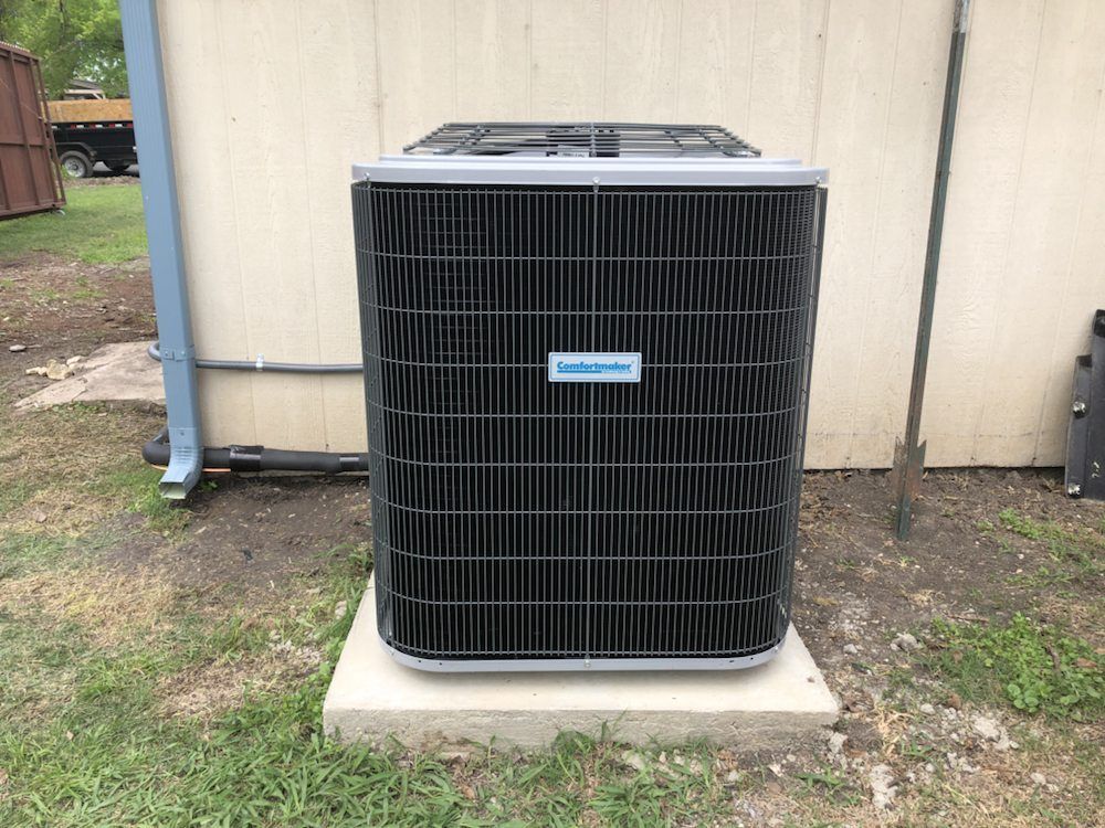 A large air conditioner is sitting on top of a concrete base.