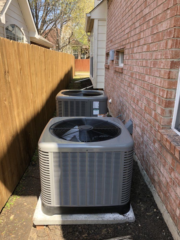 Three air conditioners are sitting on the side of a brick house.