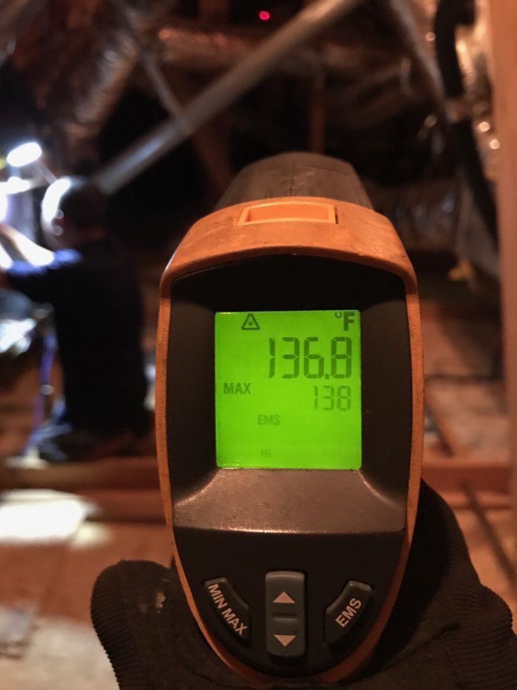 A hand is holding a thermometer that reads 136.8 degrees