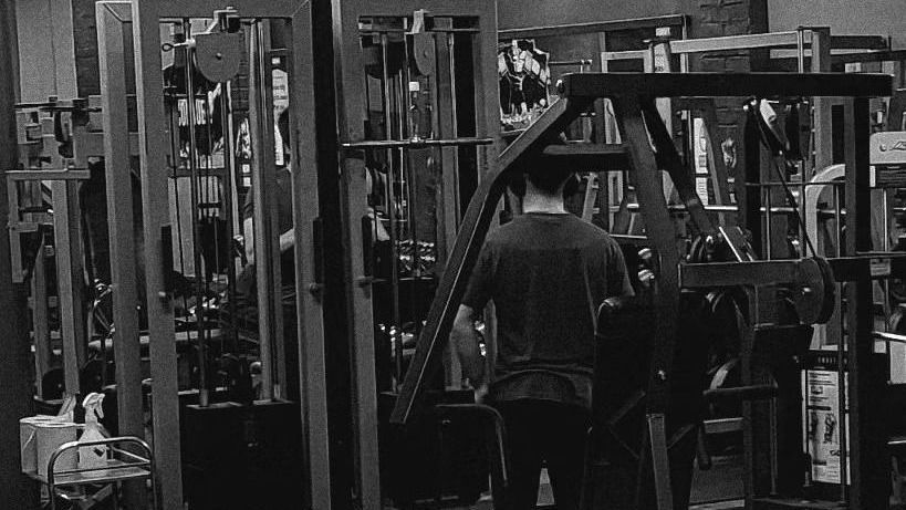 A black and white photo of a man standing in a gym.