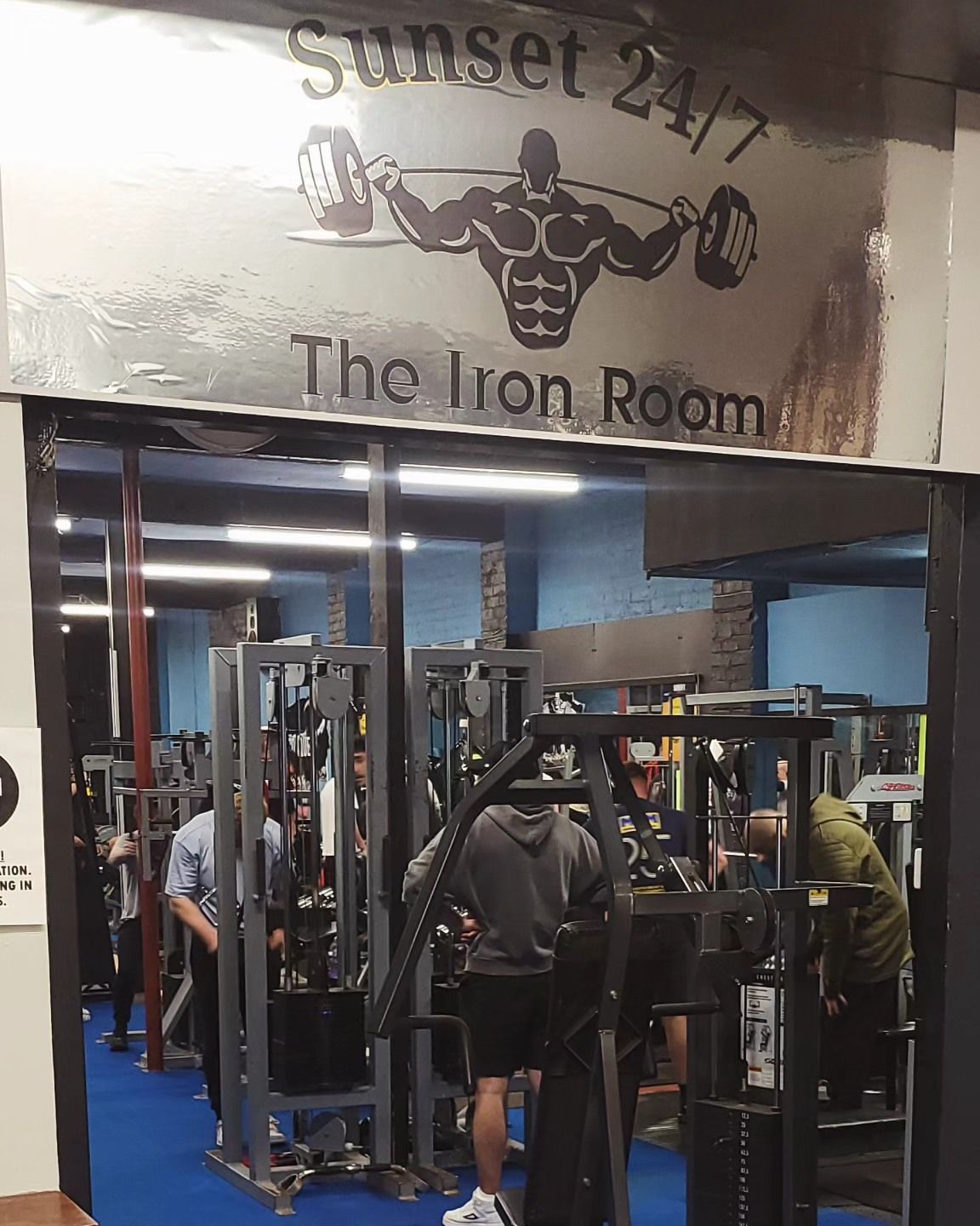 A gym with a sign that says sunset 24/7 the iron room