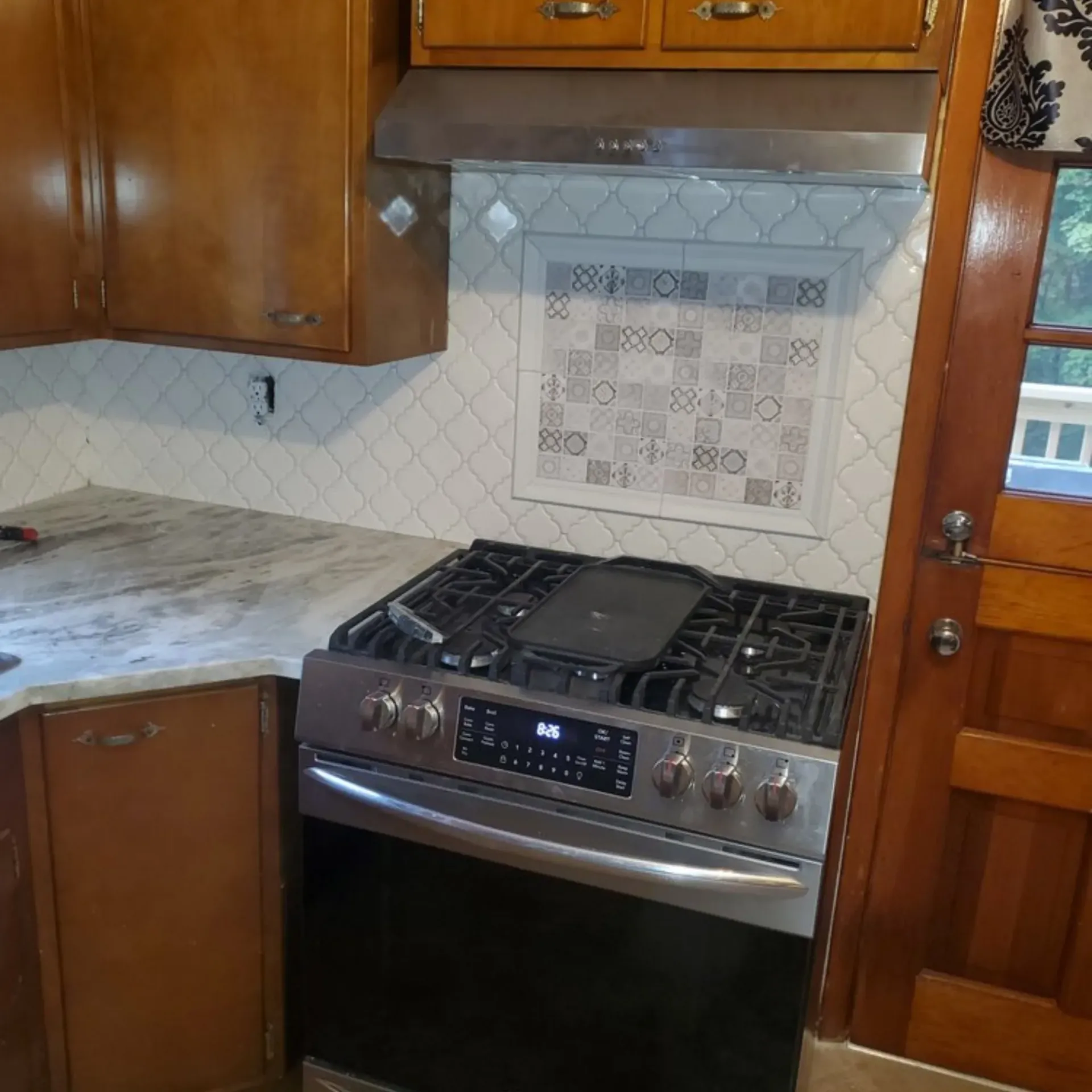 The 5 Contracting- A kitchen with a stove top oven and wooden cabinets