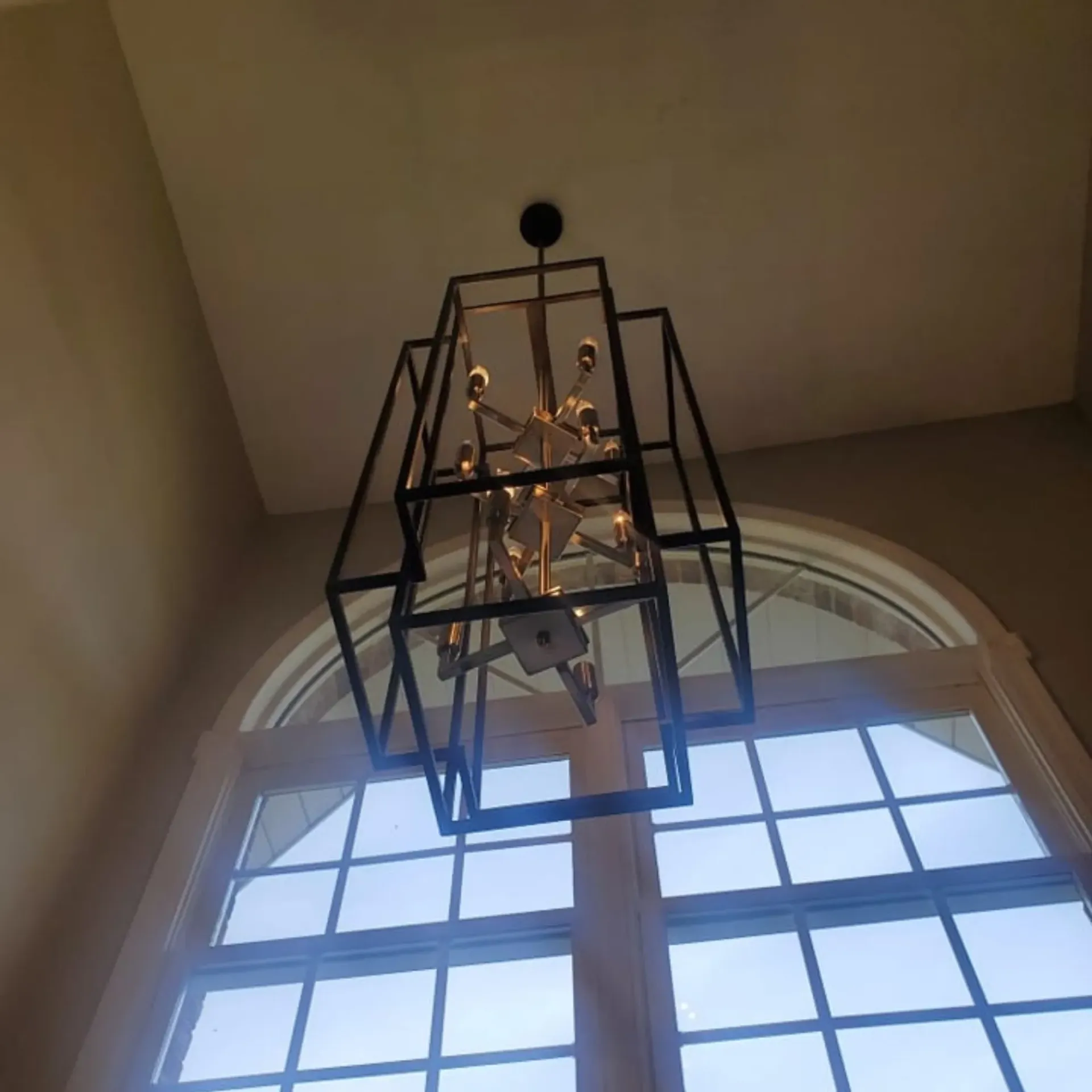 The 5 Contracting- A chandelier is hanging from the ceiling in front of a window