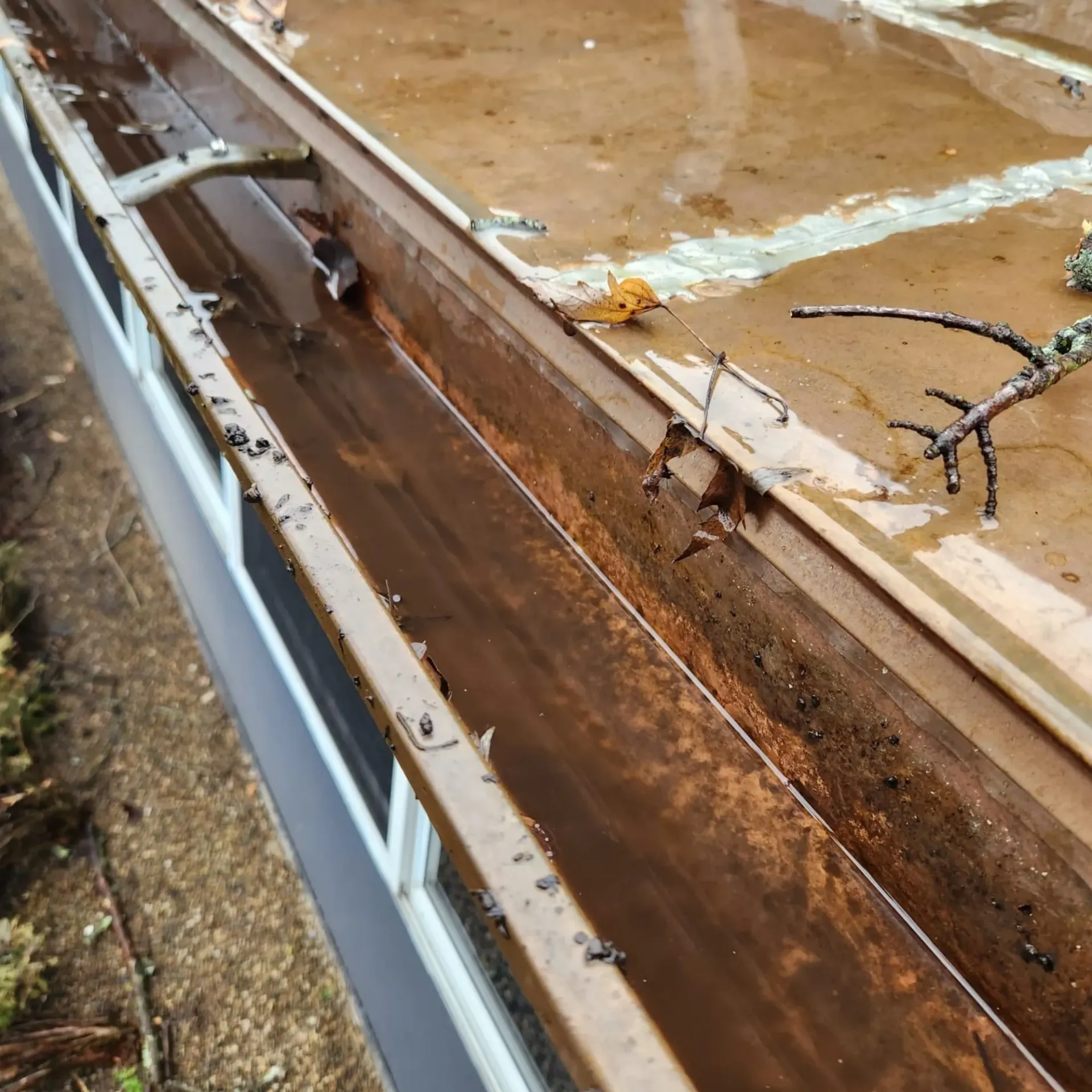 The 5 Contracting- A close up of a rusty gutter on a house