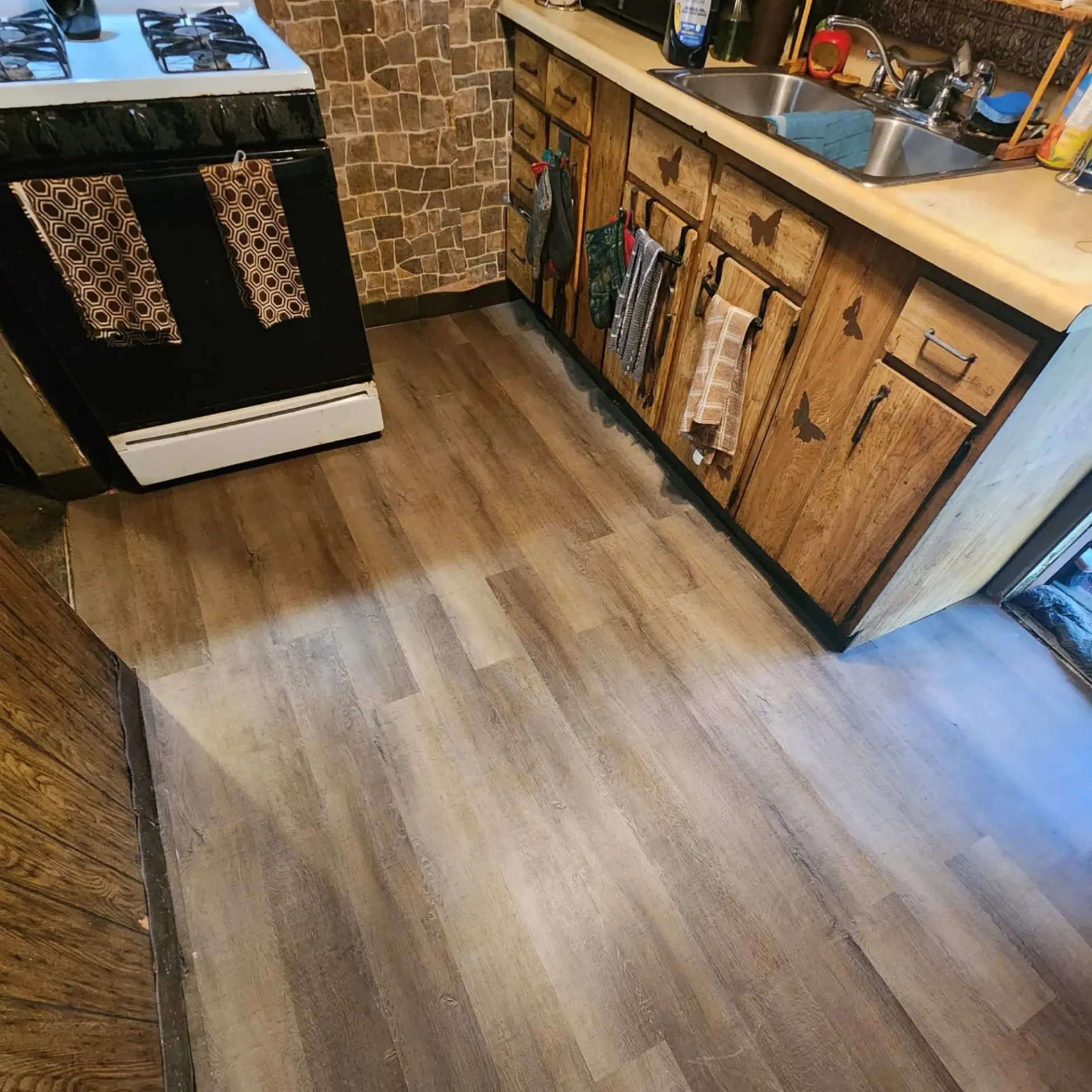 The 5 Contracting- A kitchen with a stove , sink , and wooden cabinets.