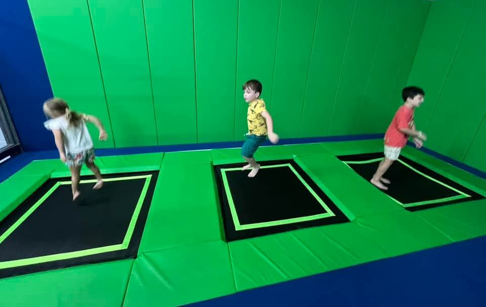 A group of children are standing in a circle with their heads together and smiling.
