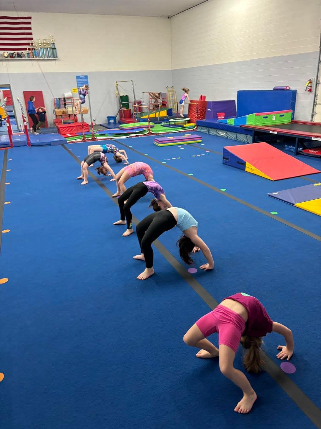 A baby in a striped tank top is hanging from gymnastic rings