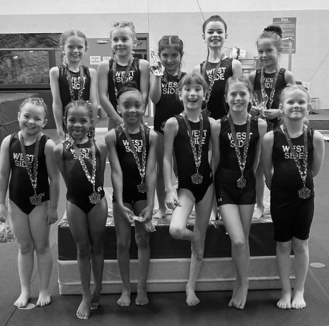 A female gymnast is standing on a balance beam.