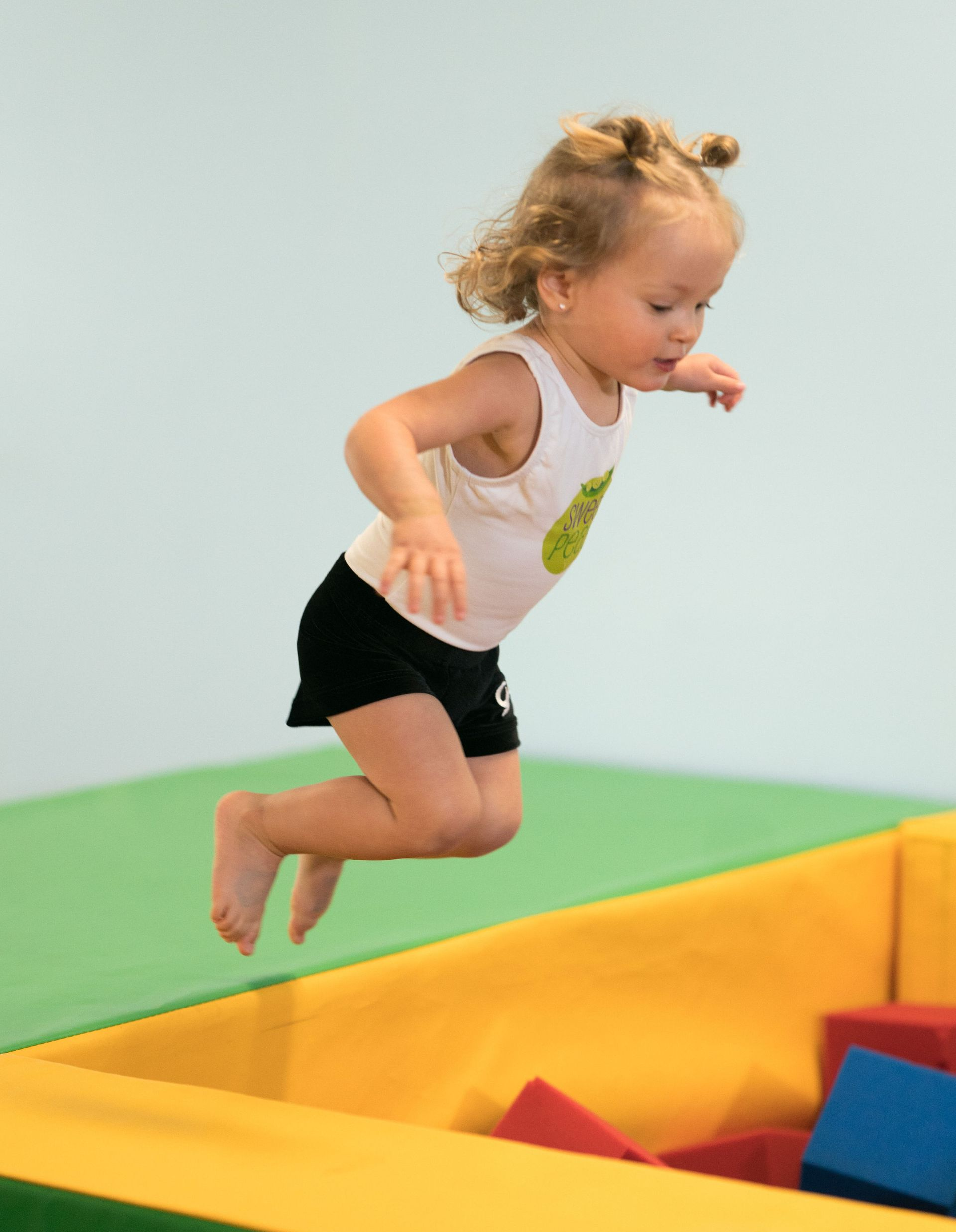 Young child jumping into a padded play area.