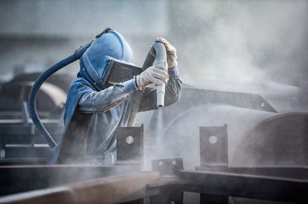 A Man Is Sandblasting A Piece Of Metal With A Machine — ADR Engineering in Collinsville, QLD
