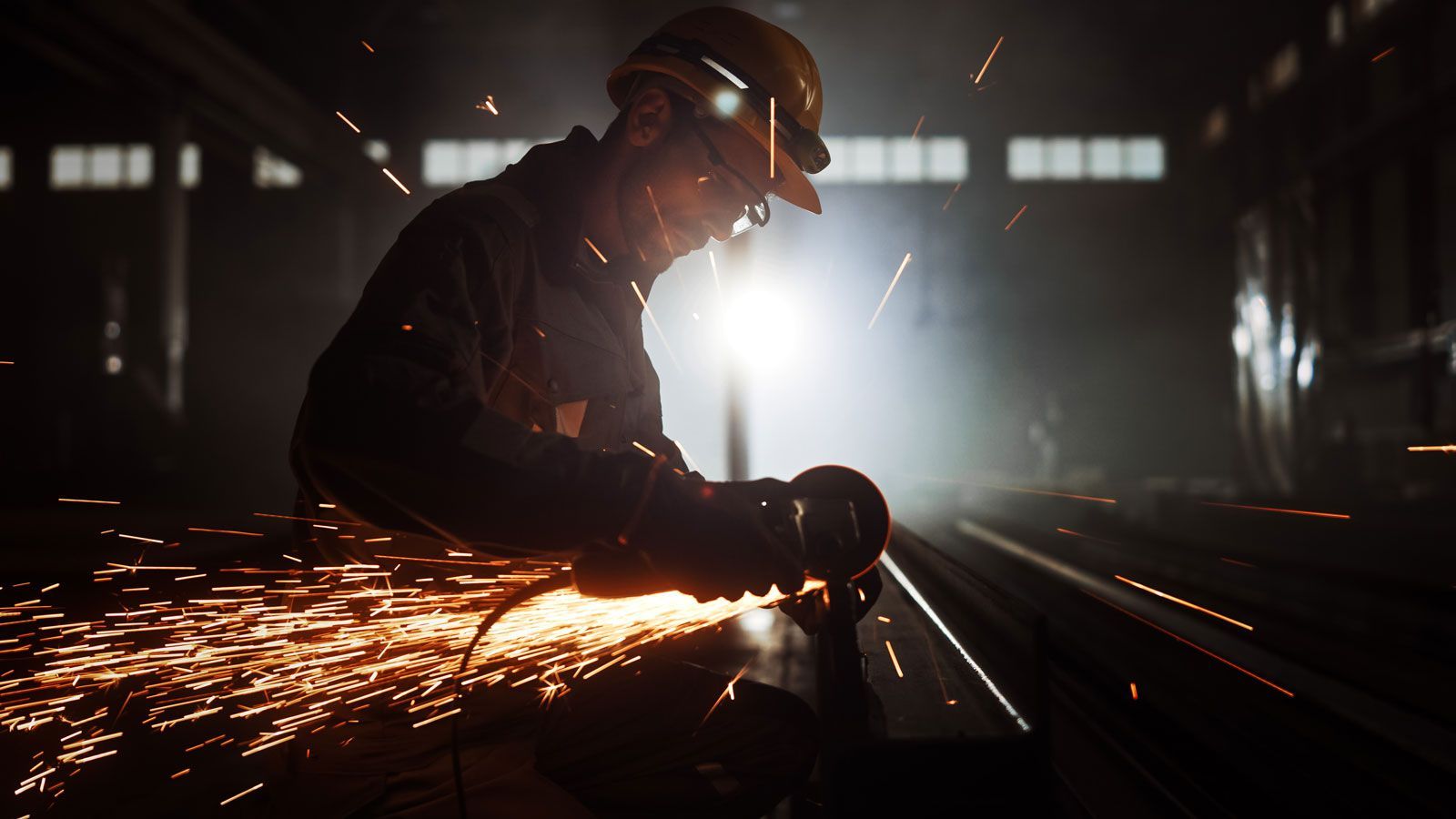 A Man Is Grinding A Piece Of Metal In A Factory — ADR Engineering in Collinsville, QLD