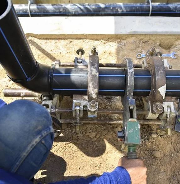 A Man Is Working On A Pipe In The Dirt — ADR Engineering in Collinsville, QLD
