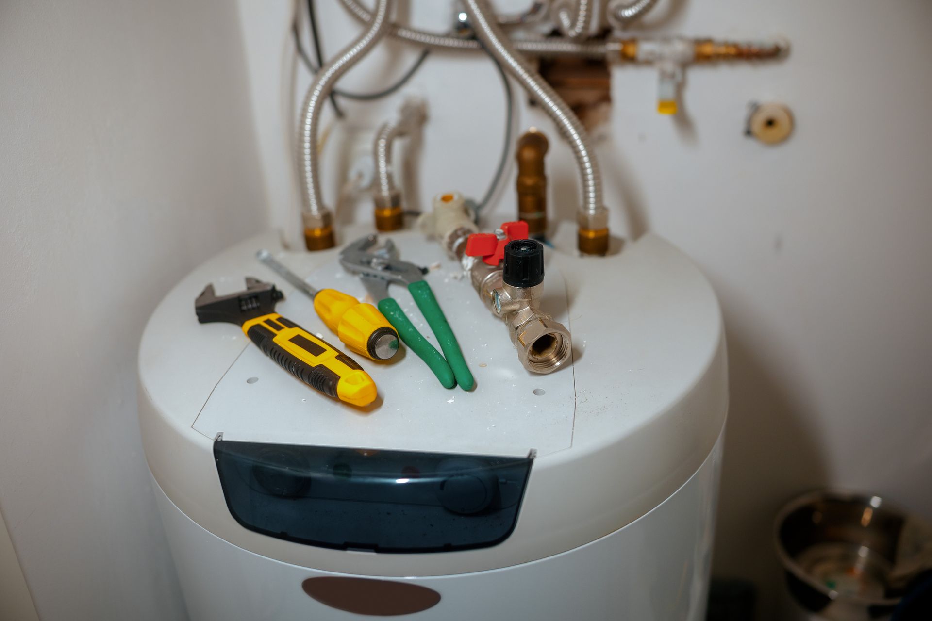 Tools and hoses arranged on top of a water heater during installation work.