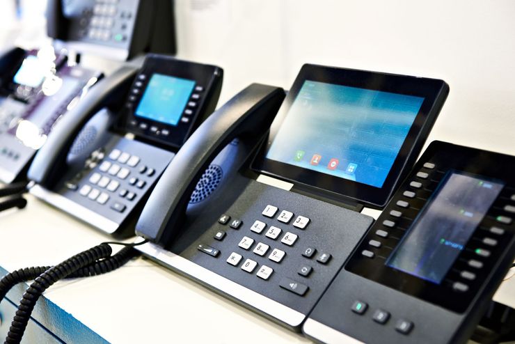 A row of telephones with screens are sitting on a table.