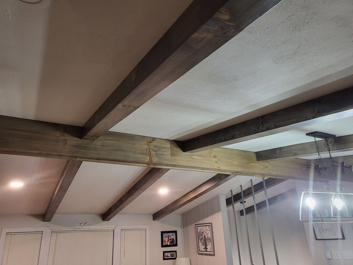 Ceiling with exposed wooden beams, recessed lights, and hanging string lights in a room