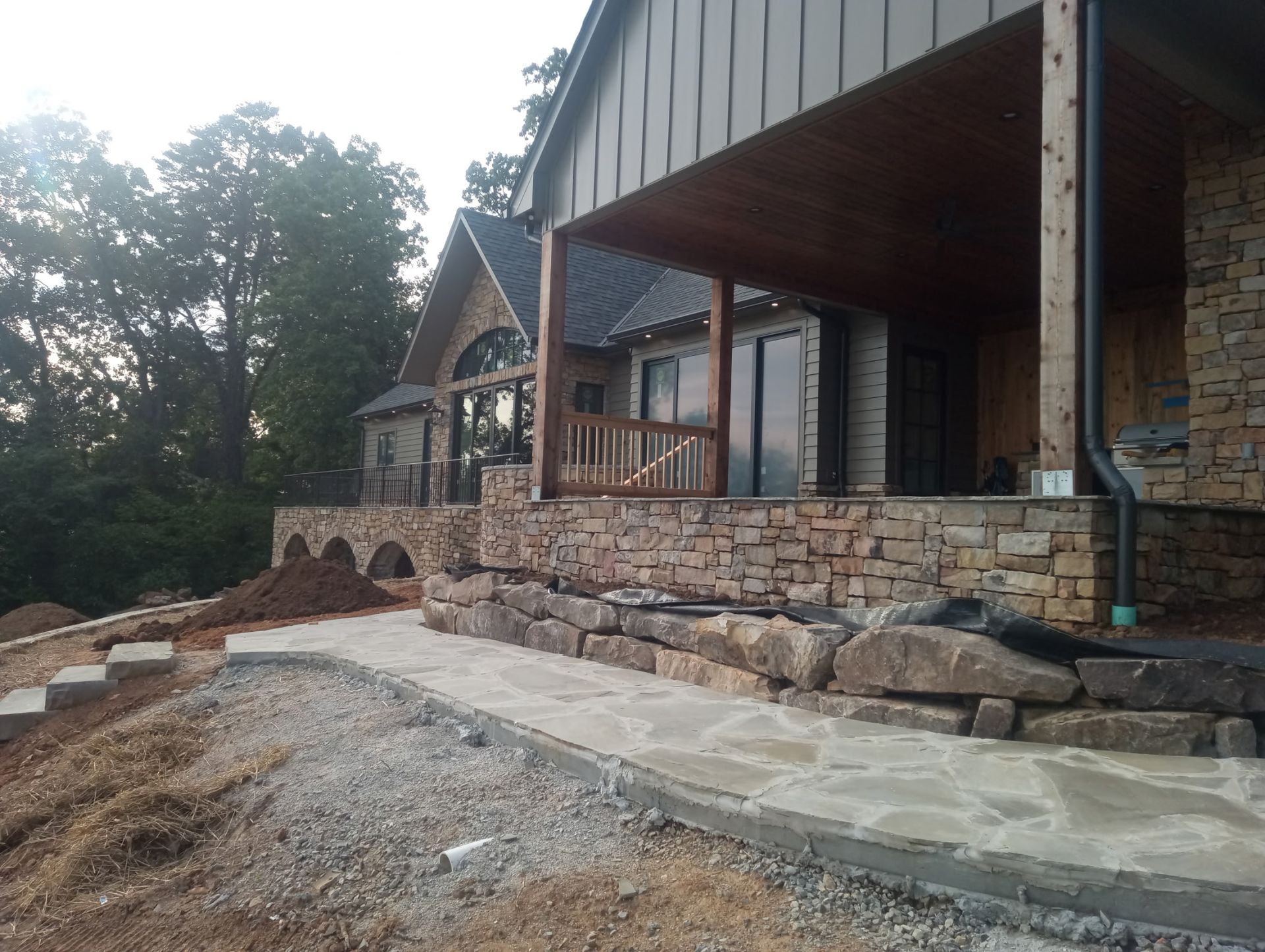 Person using a pressure washer to clean green algae from the gray siding of a house.