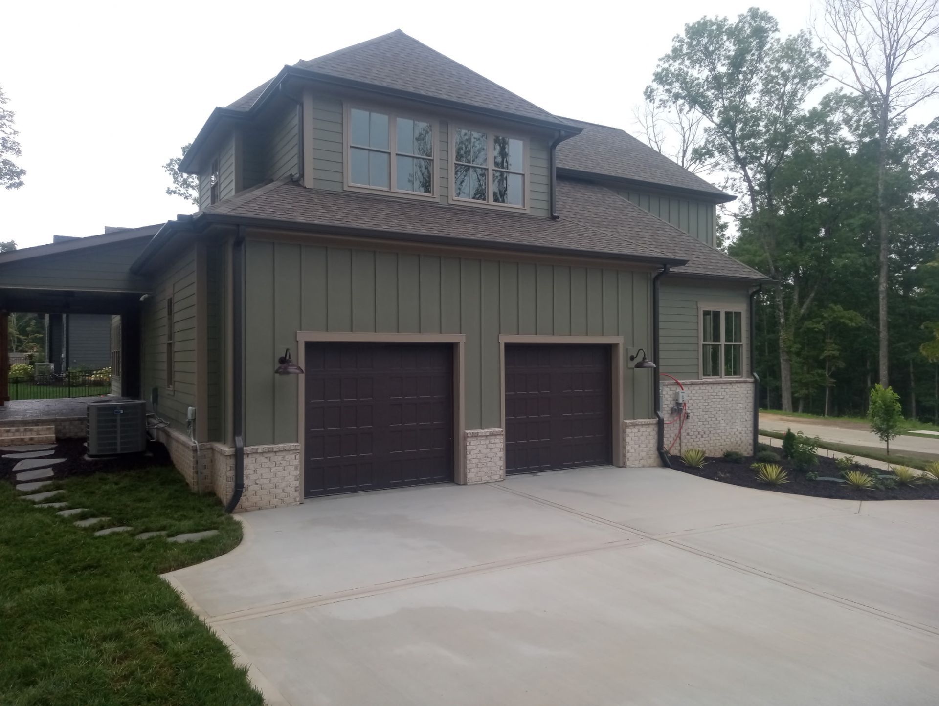 Modern two-story house with two garage doors, stone accents, and a wide driveway