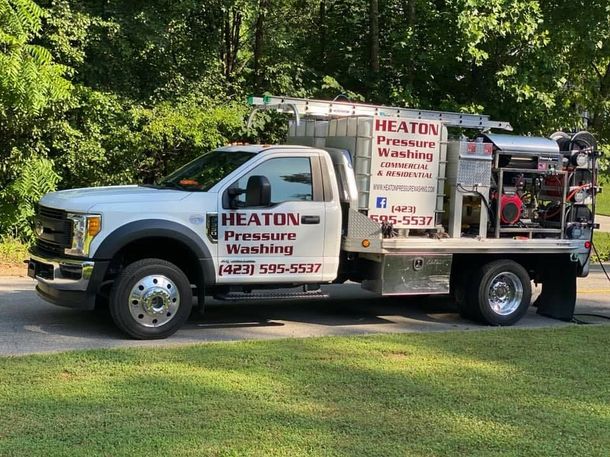 White service truck for HEATON Pressure Washing parked on grass by trees, with mounted equipment on the back