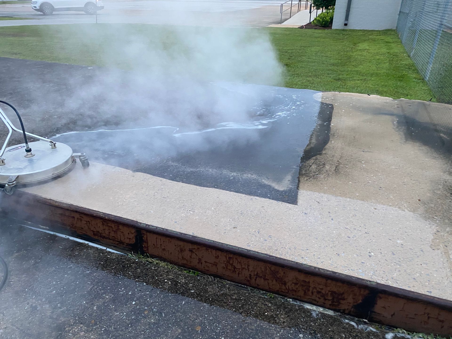 Steam rising from a wet driveway or walkway beside a lawn and brick edging
