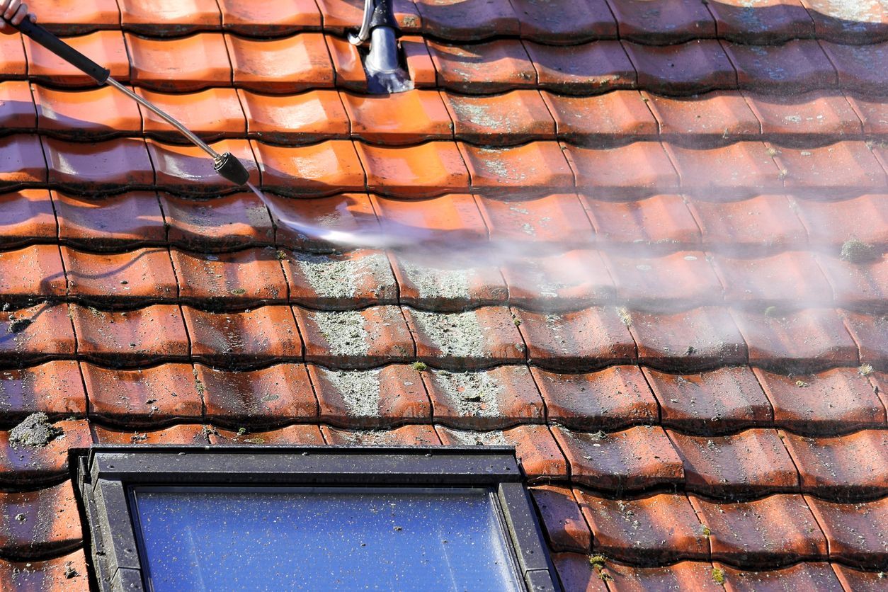 Power washing red tiled roof, removing moss.