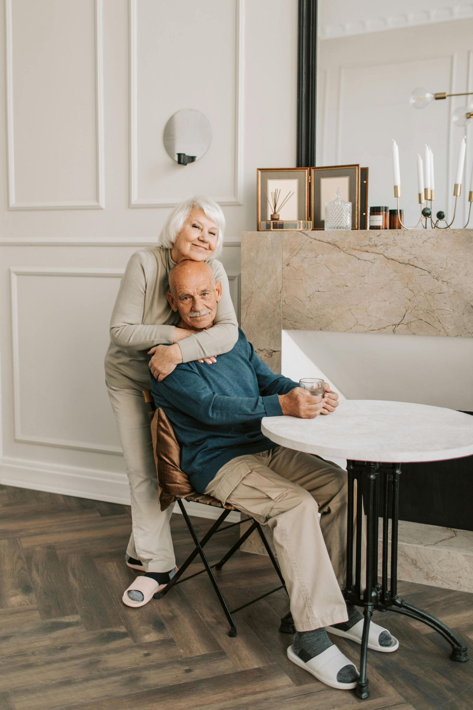An elderly couple is posing for a picture while sitting at a table.