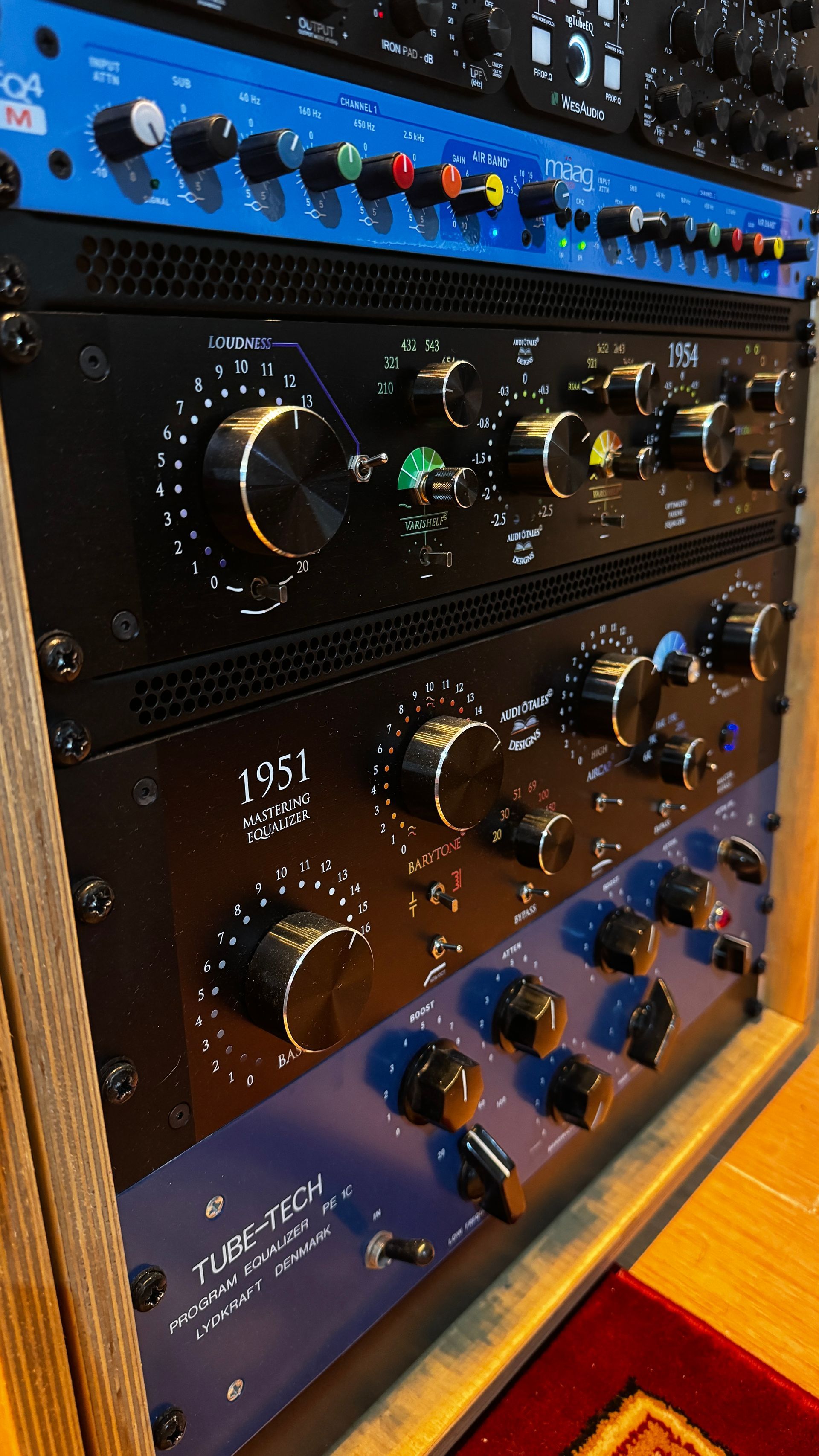 Audio equipment rack with various black and blue audio processors and controls.