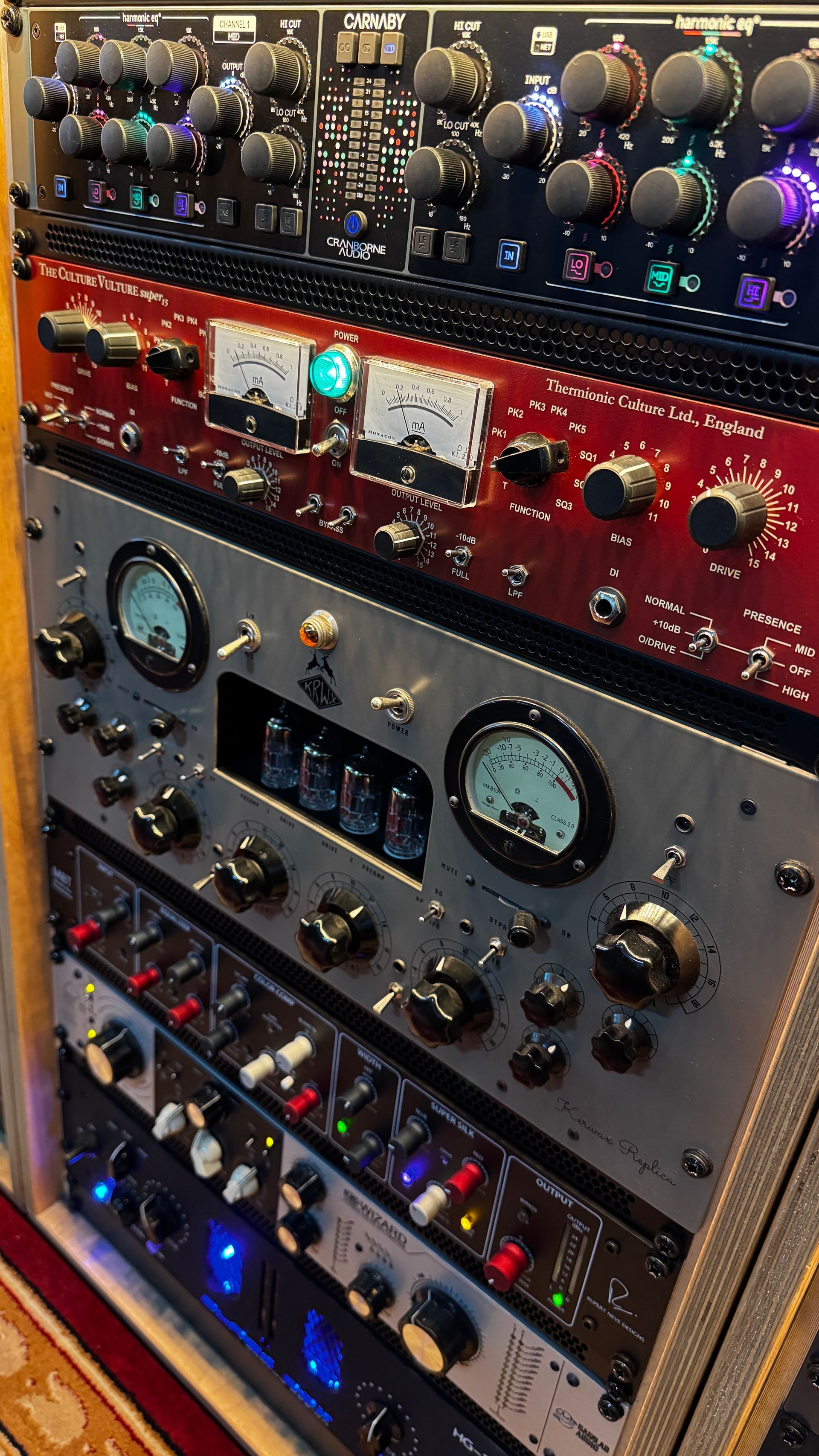 Rack of professional audio equipment with knobs, meters, and colorful lights.