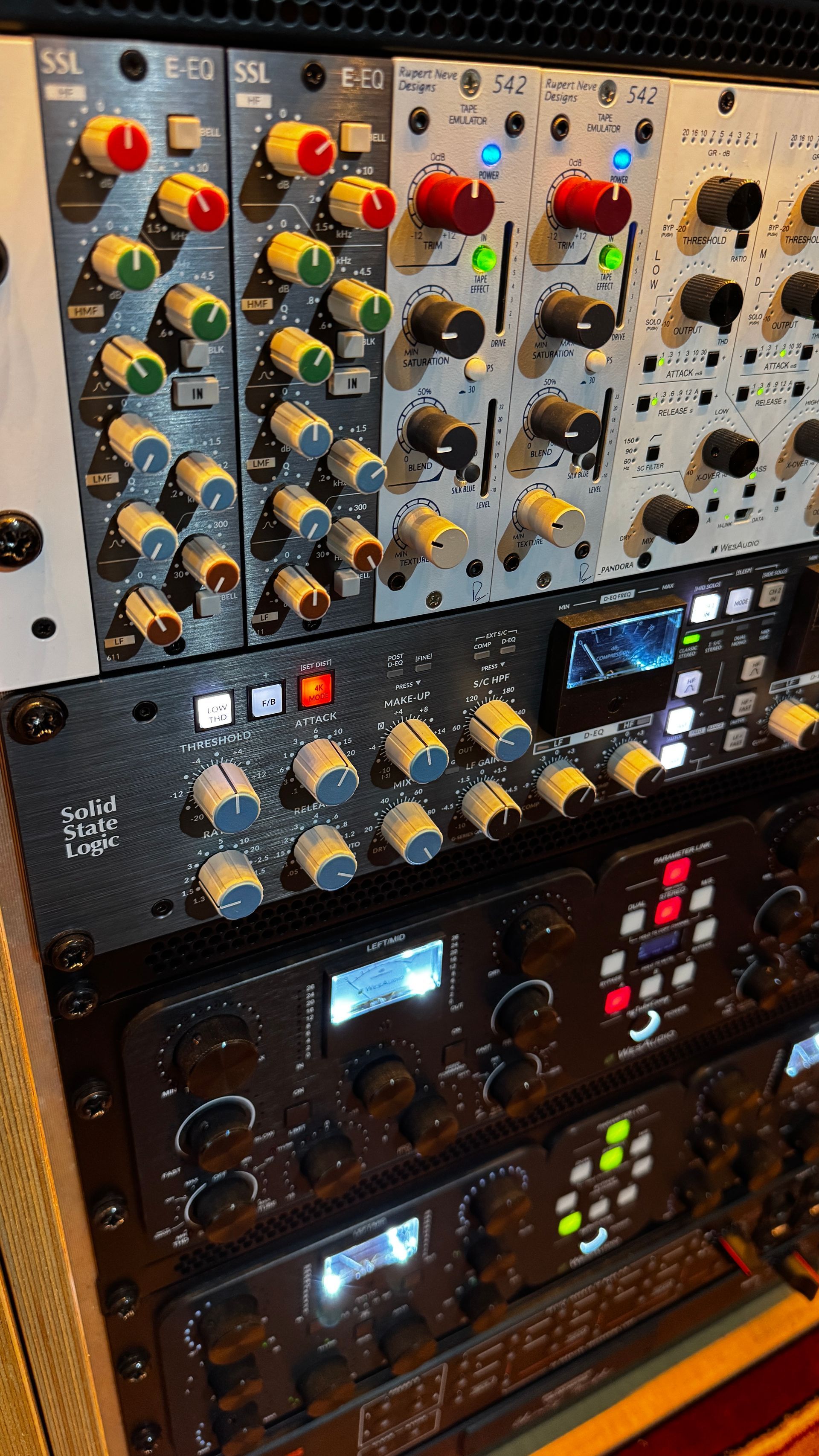 A rack of audio equipment with various knobs, buttons, and displays. Predominantly black with silver and colorful accents.