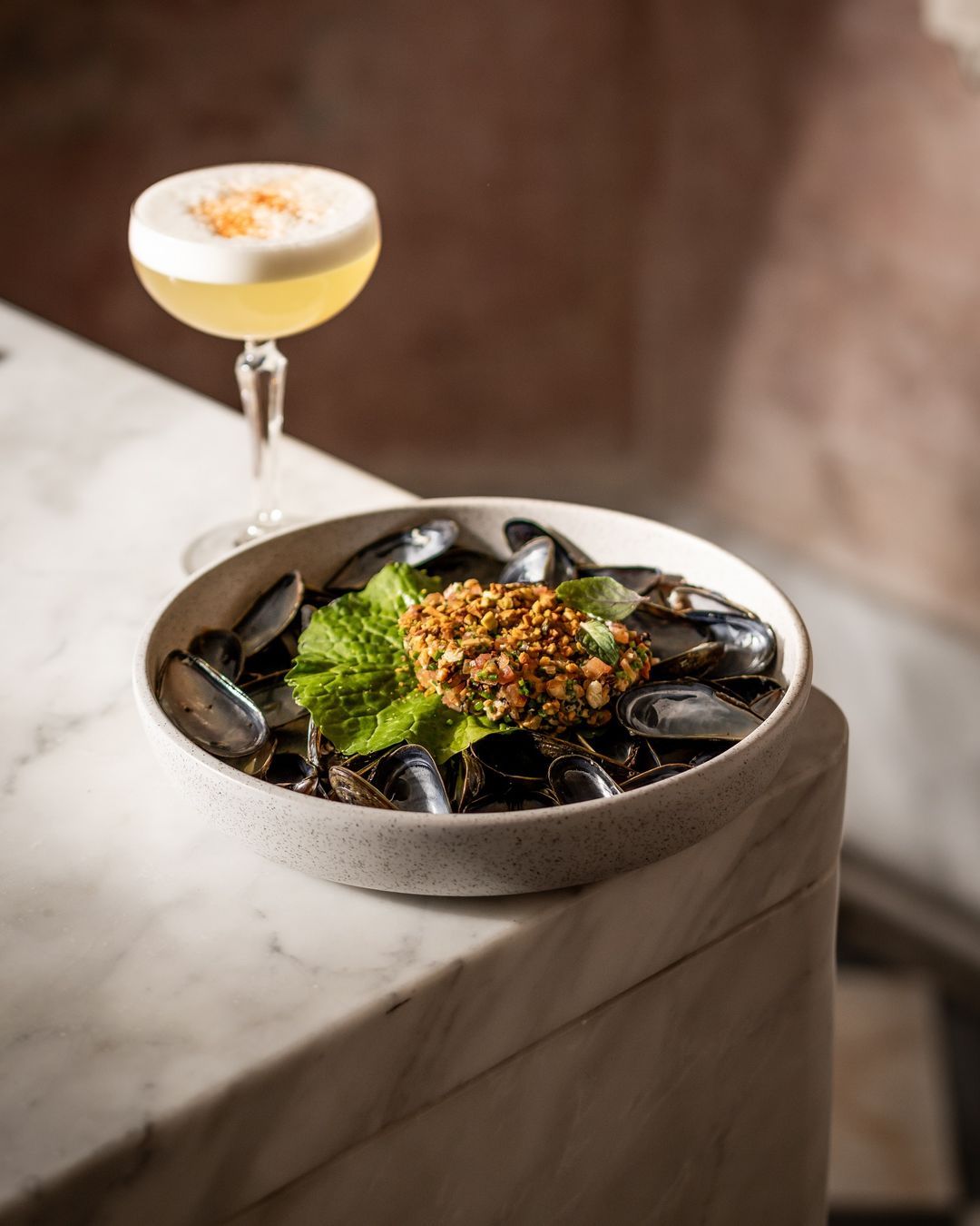 A bowl of mussels and a glass of wine on a table.