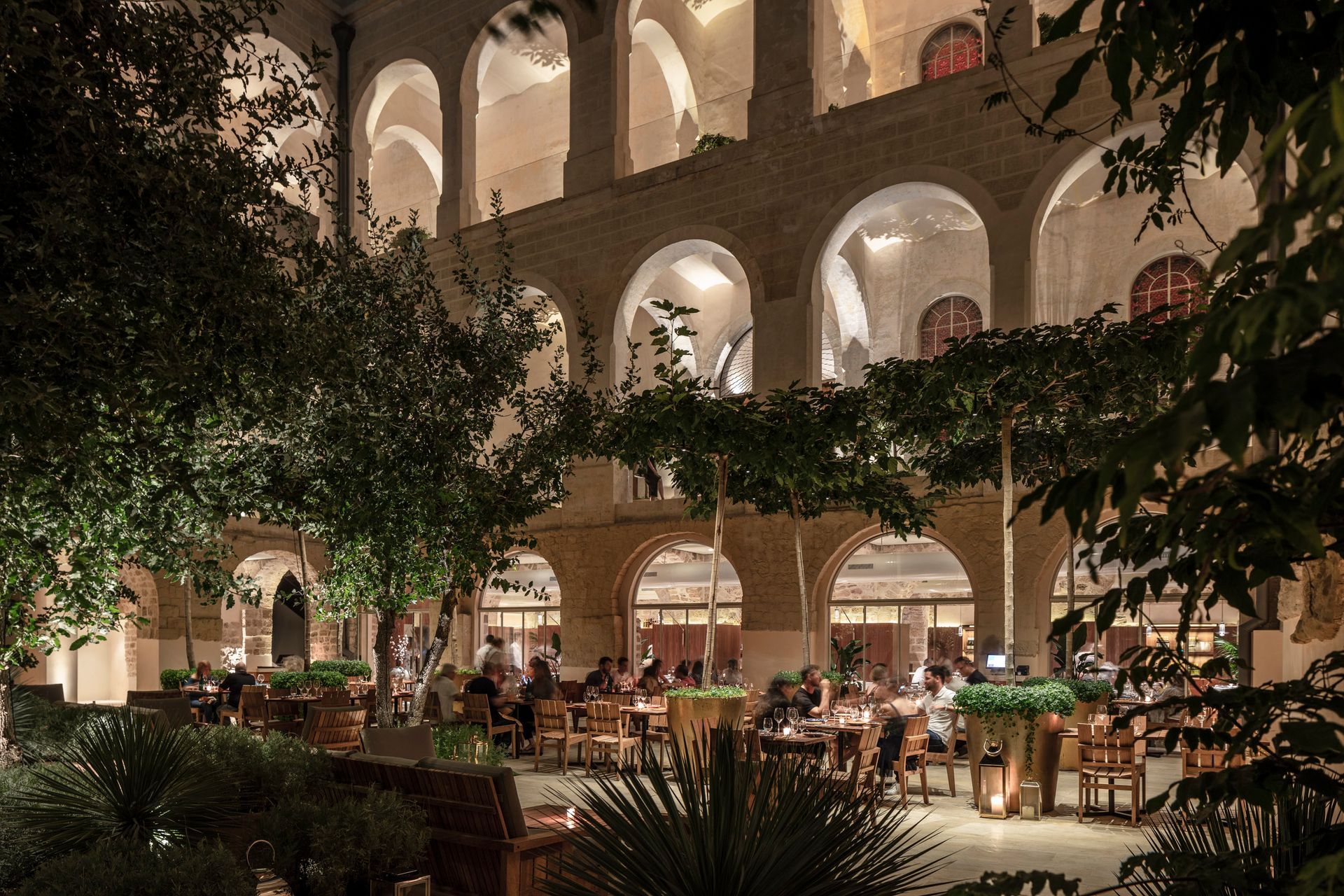 People are sitting at tables outside of a building at night